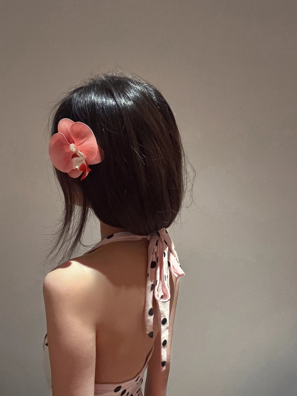 Model wearing pink orchid barrette hair clip, styled on the side of the head, elegant and natural look.