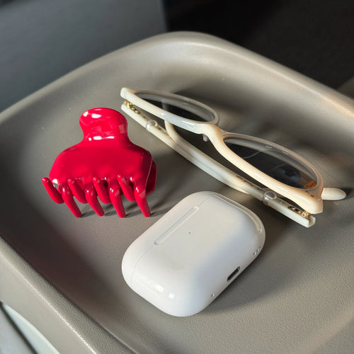 Irisa Rosa mini red claw clip lifestyle shot with earbuds and accessories